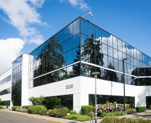 Contemporary office building in Redmond with reflective glass and lush greenery, captured on a sunny day.